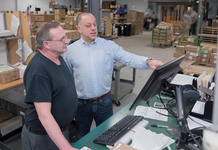 BOARDS REVIEWED: From left, Randy Broyles, shipper, and CEO Edward McMahon look at the orders going out at Epec Engineered Technologies. / PBN PHOTO/MICHAEL SALERNO