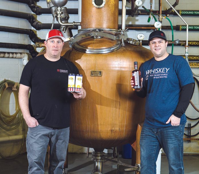 DISTILLED WISDOM: From left: Chris Guillette, distiller at Sons of ­Liberty, and Sons of Liberty CEO Mike Reppucci with one of the distillery’s whisky stills. Reppucci took advantage of a change in Rhode Island law to expand Sons of Liberty’s primarily sales-based business into an event and bar venue. / PBN PHOTO/RUPERT WHITELEY