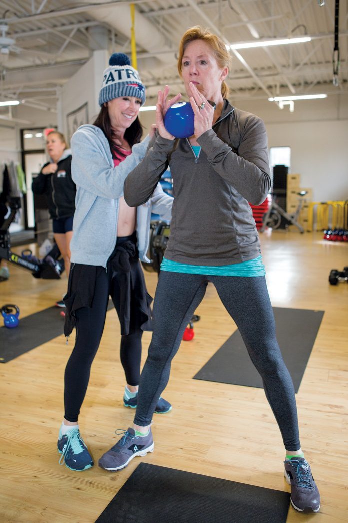 HELPING HAND: Kathy Martin, owner of Elevate Fitness in Newport, assists Tracy Mallinson of Middletown as she works out with the kettle bell during boot camp. / PBN PHOTO/KATE WHITNEY LUCEY