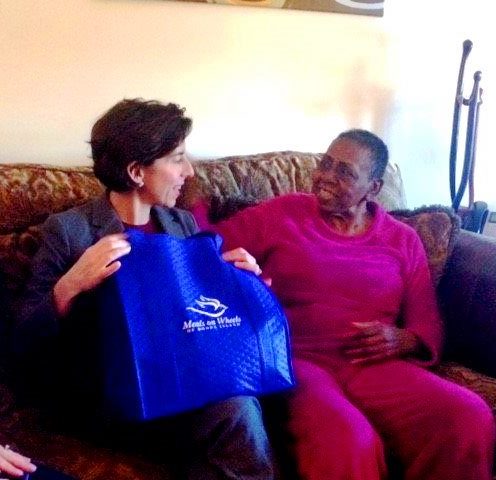 GOV. GINA M. RAIMONDO, left, delivers a meal to a woman during the 2017 March for Meals Campaign. / COURTESY MEALS ON WHEELS OF RHODE ISLAND