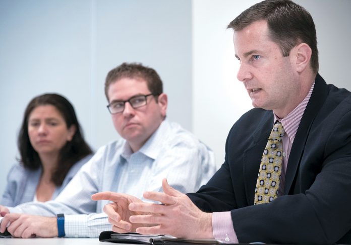 QUANTIFIED: Mark Stewart, right, Blue Cross & Blue Shield of Rhode Island’s chief financial officer, during a meeting at the company’s Exchange Street office with Catherine Mitchell, managing director, actuarial, and Sean Neylon, manager, actuarial. / PBN PHOTO/MIKE SALERNO