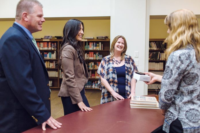 HOT SPOT: Mobile Beacon staffers, from left, Rick Lindholm, sales manager; Cristina Graham, program director; and Katherine Messier, founder and executive director, speak with Kate Aubin at the Providence Public Library about the broadband-service provider’s 4G mobile hotspot devices, which people can check out from the library – the first and now largest such program in the country.  / PBN FILE PHOTO/RUPERT ­WHITELEY