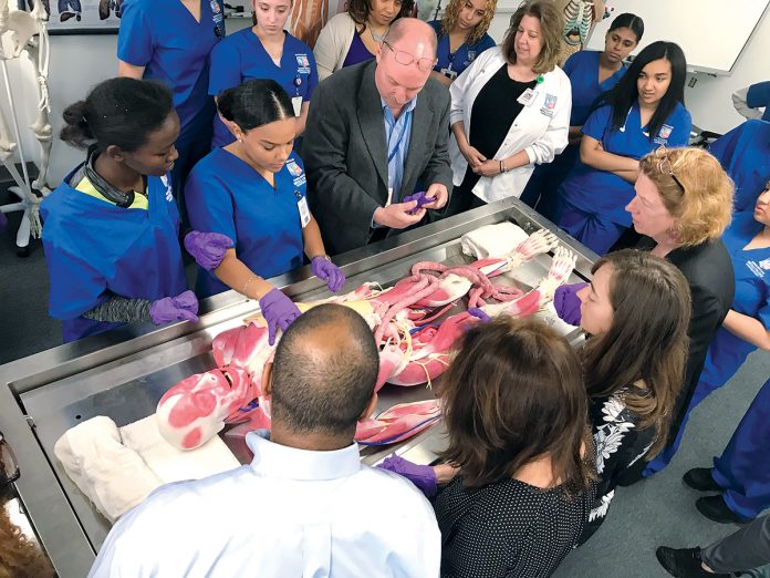 HIGH-TECH CADAVER: Michael Clancy, center top, an anatomy professor at the Rhode Island Nurses Institute Middle College in Providence, works with nursing students on Joy, a synthetic cadaver featuring replaceable muscles, bones, organs, veins and arteries made from materials that mimic live tissue.  / COURTESY RHODE ISLAND NURSES INSTITUTE MIDDLE COLLEGE