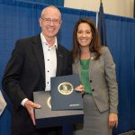 MIKE BRANDMEIER, president and CEO, Toray Plastics (America), Inc., accepts a Virginia state flag from Angela Navarro, Deputy Secretary of Commerce and Trade of the Commonwealth of Virginia, during a ribbon cutting at Toray’s PEF Division in Front Royal. / COURTESY TORAY PLASTICS (AMERICA) INC.