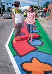 WALKING TOUR: Marta V. Martinez, left, executive director of Rhode Island Latino Arts and host of the Broad Street neighborhood walking tour, stops along the route with Tamara Diaz, the artist who painted the mural they are standing on.  / PBN PHOTO/MICHAEL SALERNO