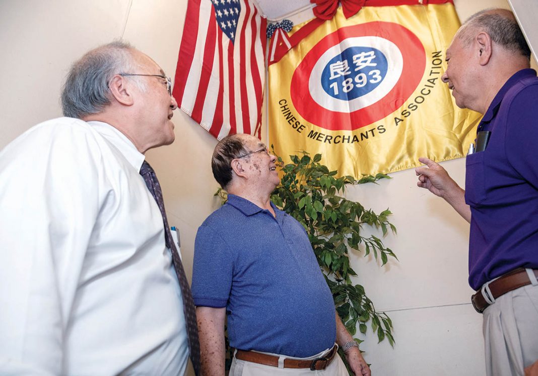 FAMILY CONNECTION: Charles Chin, left, president of the Rhode Island chapter of the On Leong Chinese Merchants Association in Cranston, Peter Kwong, center, and Edward Moy look at an association flag. Moy’s grandfather was a past president of the association.
/ PBN PHOTO/MICHAEL SALERNO FAMILY CONNECTION: Charles Chin, left, president of the Rhode Island chapter of the On Leong Chinese Merchants Association in Cranston, Peter Kwong, center, and Edward Moy look at an association flag. Moy’s grandfather was a past president of the association.
/ PBN PHOTO/MICHAEL SALERNO