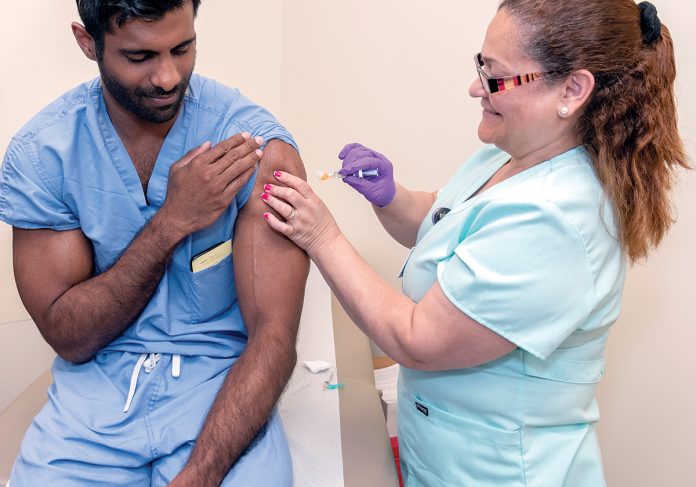 PRELIMINARY SHOT: Gladys Torre, a medical assistant at Brown Medicine, administers the yellow-fever vaccine to Dr. Jacob Babu, an orthopedic surgery resident at Brown Medicine, before he travels to Africa.   / PBN PHOTO/MICHAEL SALERNO