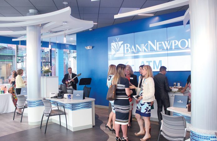 OPEN FOR BUSINESS: Guests mingle and converse at the new BankNewport branch on Dorrance Street in Providence during the open house event June 26 celebrating the branch’s grand opening. The branch replaced the former AAA branch with a full redesign, replacing the teller counter with pod stations for customer seating, making the space more open. The full-service branch also includes two indoor personal teller machines. / After photos: PBN PHOTOS/JAMES BESSETTE OPEN FOR BUSINESS: Guests mingle and converse at the new BankNewport branch on Dorrance Street in Providence during the open house event June 26 celebrating the branch’s grand opening. The branch replaced the former AAA branch with a full redesign, replacing the teller counter with pod stations for customer seating, making the space more open. The full-service branch also includes two indoor personal teller machines. / After photos: PBN PHOTOS/JAMES BESSETTE