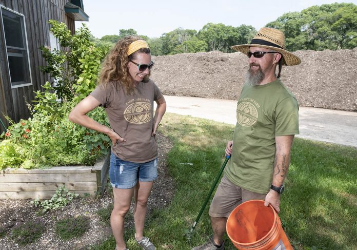 COMPOST CENTRAL: Jayne Merner Senecal, owner of Earth Care Farm in Charlestown, the largest commercial-scale licensed composting facility in the state, with Jeff Glover, farm support, who is holding a grabber and bucket that he uses to clean the piles of unwanted items. / PBN PHOTO/MICHAEL SALERNO