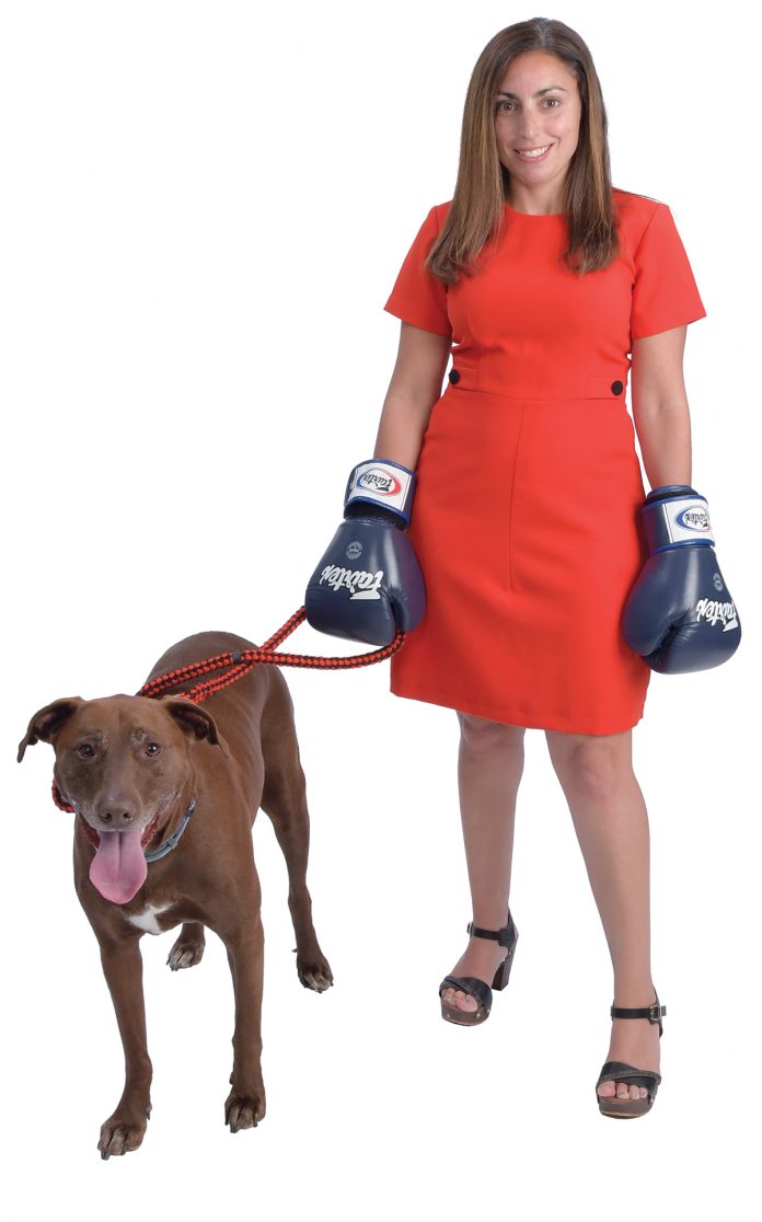 the prop: Rebecca Plonsky’s dog’s name is Gronk – after Rob Gronkowski of the Patriots. “We rescued him five years ago.” The boxing gloves for muay thai kickboxing help her to stay humble and healthy. / PBN PHOTO/MIKE SKORSKI