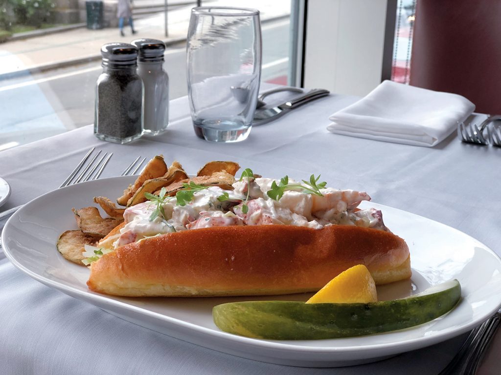 FRESH CATCH: The lobster roll at Hemenway’s restaurant in Providence is made with fresh, steamed and hand-picked Maine lobster, which is tossed with crème fraiche, cucumber dressing, fresh herbs and lemon, and is served on a fresh-baked brioche roll with hand-cut zucchini chips.  / COURTESY HEMENWAY’S/LUCAS PRESTON