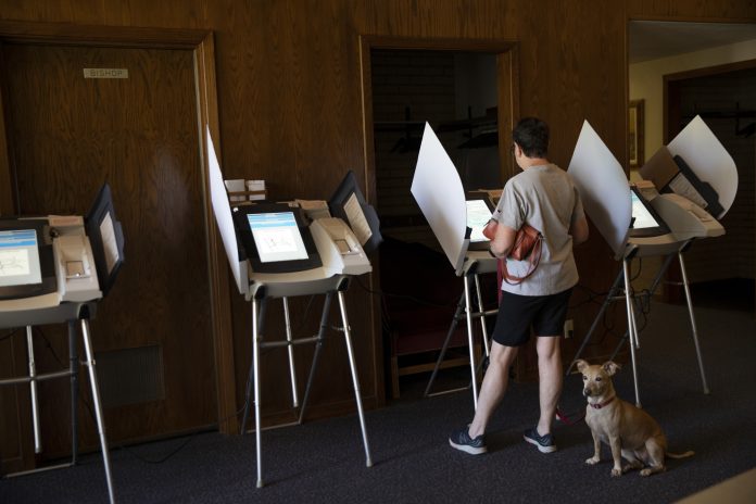 IN A RECENTLY RELEASED CBS NEWS POLL, nearly two-thirds of U.S. voters rated the economy as either very good or somewhat good. Here a voter casts a ballot with her dog at a polling location in Utah. / BLOOMBERG NEWS FILE PHOTO/KIM RAFF