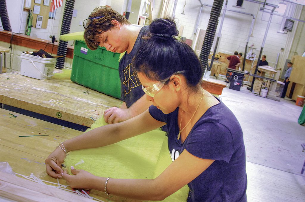 BUILDING SOMETHING: Evelyn Romero and Ron Banner refit filter material positioned on the back wall of a spray paint booth in the construction lab at Westerly High School as part of a P-TECH construction career program.   / PBN PHOTO/ BRIAN MCDONALD 