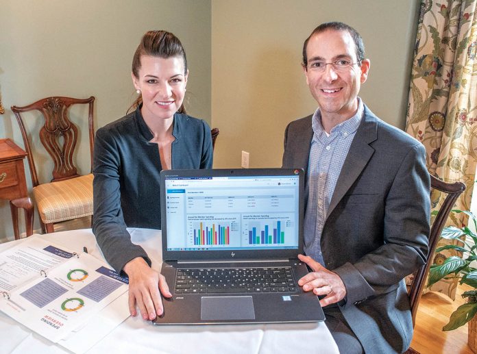 DATA-DRIVEN: Shannon Shallcross, CEO, and Mark Regine, chief epidemiologist for BetaXAnalytics, with a spreadsheet showing health spending. The data report is used to help companies identify where they can save money on health care spending.   / PBN PHOTO/MICHAEL SALERNO