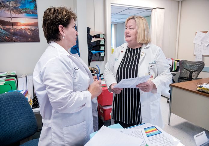 INFECTION PREVENTION: Lee Ann Quinn, right, director of infection prevention and control for South County Hospital in South Kingstown, speaks with Kristen Whelan, infection prevention, employee health analyst and flu clinic coordinator.  / PBN PHOTO/MICHAEL SALERNO
