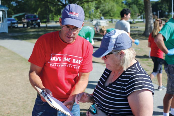 BEACH CLEANUP: Save The Bay Executive Director Jonathan Stone, left, speaks with a volunteer at a cleanup in the Oakland Beach neighborhood of Warwick during last year’s International Coastal Cleanup Day. Above right, a logo in support of Question No. 3 on next month’s ballot created by Save The Bay.   / COURTESY SAVE THE BAY