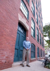 FORMER FACTORY: Jewelry District Association member Olin Thompson lives on the eighth floor of a former jewelry factory on Chestnut Street in Providence. Thompson, standing in front of his building, gives free, two-hour walking tours of the neighborhood.  / PBN PHOTO/MICHAEL SALERNO