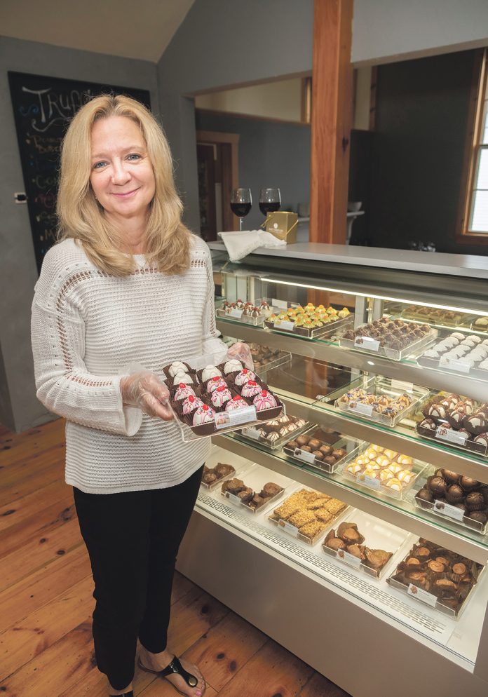 SPECIALTY STORE: Christine M. Bourget is the owner of The Captain’s Table in North Kingstown, specializing in gifts and specialty foods. Bourget is holding a tray of chocolates, with “Wedding Cake” at the rear and “Birthday Party” upfront.  / PBN PHOTO/MICHAEL SALERNO