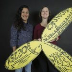 Shey Rivera (left) and Shauna Duffy (right) pose with a recreation of the iconic AS220 propeller. On Dec. 31 Rivera will depart the nonprofit arts group to pursue personal endeavors while Duffy has been promoted to a new role for the group, executive director. / COURTESY AS220