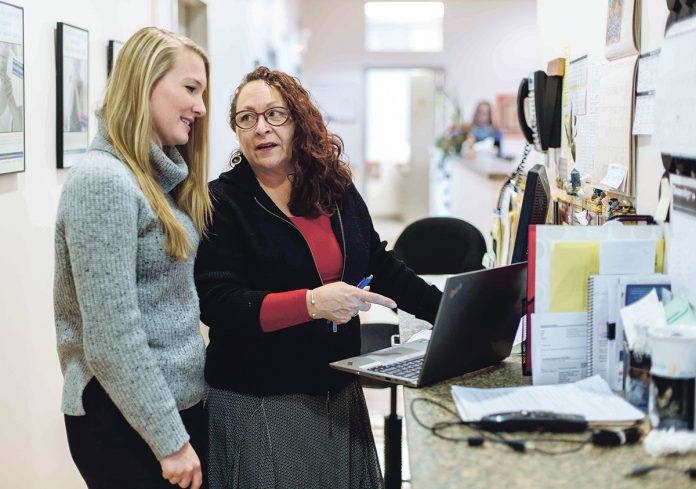 RECORD TIME: Brown University researchers have published a study showing that electronic health records are more stressful for physicians than they are helpful. At Coastal Medical, practice nurses, such as Margaret Hatzpanian, right, now handle most clinical documents and administrative tasks previously handled by doctors. At left is Stephanie Nunes, nurse practioner.  / PBN PHOTO/ RUPERT WHITELEY