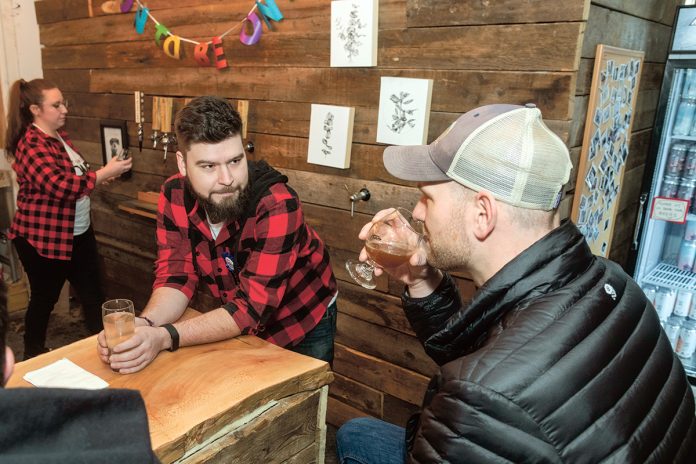 PASSIONATE BREWER: Morgan Snyder Jr., center, is co-owner of Buttonwoods Craft Brewing. Snyder has worked in the brewing industry, including home brewing, since graduating college in 2011. Adam Henderson of East Providence tastes the “30 Is The New 40” double IPA. At left is bartender Jennie Paquin. / PBN PHOTO/MICHAEL SALERNO