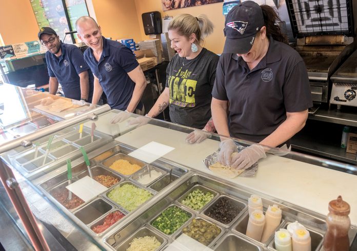 ENTREPRENEUR AT HEART: Matt Rusconi, second from left, franchise owner of Moe’s Southwest Grill in East Providence, with, from left, Remon Gergis, director of operations; Alyssa Hawksley, shift lead; and Gail Brisson, general manager, as the team prepares food.                                                                                     /   PBN PHOTO/MICHAEL SALERNO