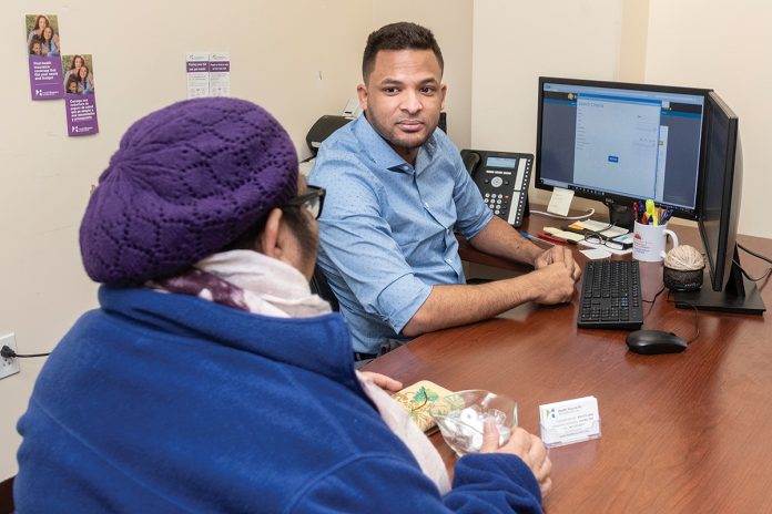 HELPING HAND: Customer-service representative Ramon Chevas German, right, assists a client with health insurance at a HealthSource RI center in East ­Providence.  / PBN PHOTO/MICHAEL SALERNO