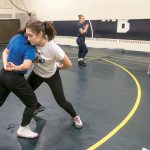 BEAT THE STREETS: Maricruz Flores, 12, left foreground, and Skylah Chakouian, 16, right foreground, spar as part of the Beat the Streets wrestling program at Moses Brown High School. In the background is Director Jacque Davis. At right are Alezia Greman, left, 10, and Ivy Latino, 7.  / PBN PHOTO/MICHAEL SALERNO
