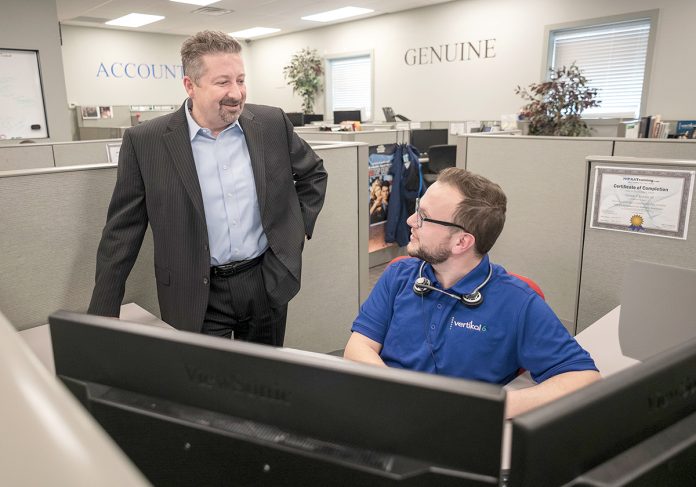 RECRUITING KEY: CEO Rick Norberg, left, speaks with Teddy Kennedy, service desk apprentice, at Vertikal 6 in Warwick. Norberg said the company’s full-time apprenticeships have become the key to recruiting and developing employees.  / PBN PHOTO/MICHAEL SALERNO