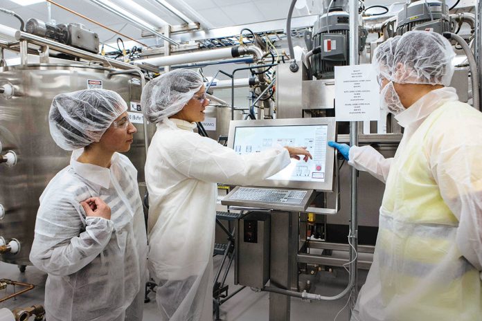 LARGER SPACE: Edesia, a maker of food products for customers such as UNICEF that ship goods overseas to feed malnourished children, outgrew its original facility in Providence and made the move to the Quonset Business Park in North Kingstown in 2016, opening an 83,000-square-foot, high-tech factory. From left, Executive Director Maria Kasparian, founder and CEO Navyn Salem and HMI Controller Jorge Campos work in the factory.  / PBN PHOTO/RUPERT WHITELEY