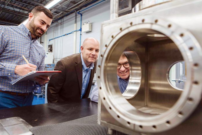 A KEEN EYE: President and CEO George Mock, right, inspects a piece of machinery at Nye Lubricants, along with Jason Galary, center, director of research and development, and Gus Flaherty, manager of engineering development and applications.  / PBN PHOTO/RUPERT WHITELEY