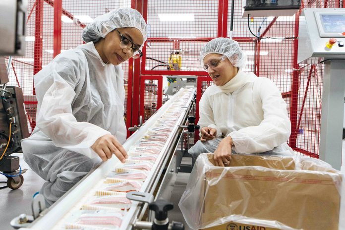 FOOD INSPECTORS: Employee Maria Velez, left, and CEO Navyn Salem check food packages as they move along the production line at the Edesia plant in North Kingstown.  / PBN PHOTO/RUPERT WHITELEY