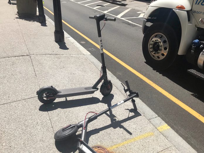E-SCOOTERS: A couple of Bird electronic scooters are photographed on a sidewalk in Providence. Bird is one of two companies operating the scooters in the capital city, which requires the scooter companies to cover the city with a general-liability insurance policy of at least $1 million in value.  / PBN PHOTO/CHRIS BERGENHEIM
