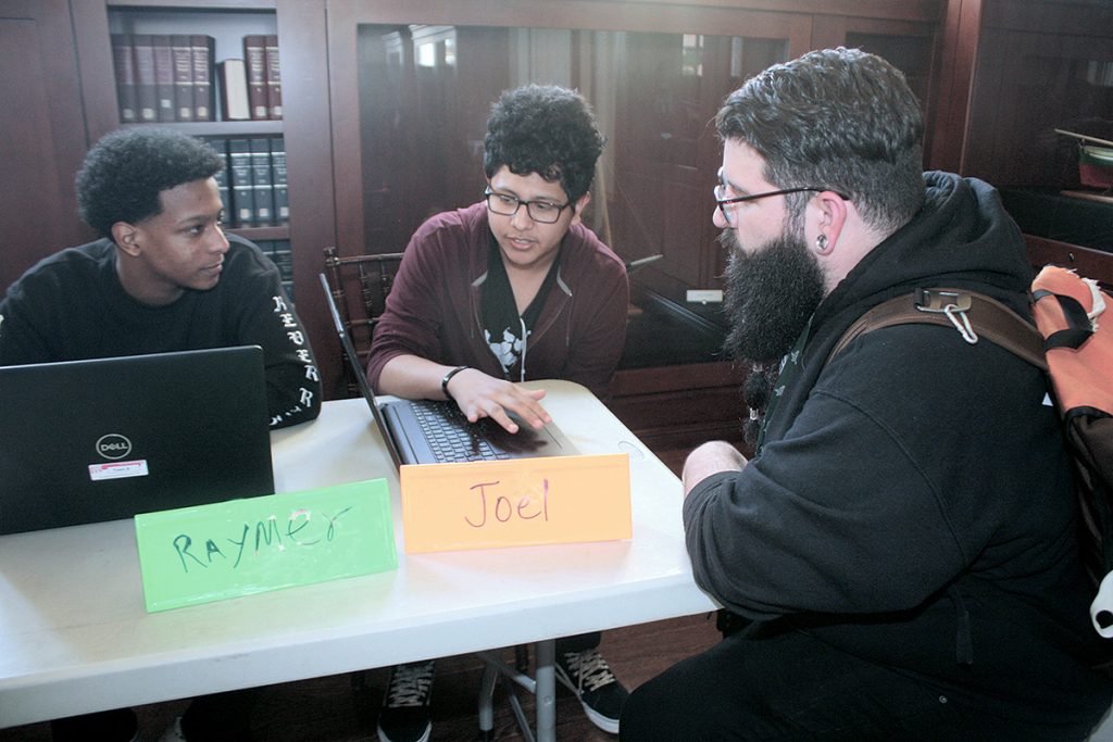 TEEN CODERS: From left, Raymer Peraota, 17, and Joel Monterroso, 16, both of Providence, discuss final assignments for Teen Rhode Coders, the library’s free computer-programming course for youths, with Kevin Cordeiro, a Trinity Academy for the Performing Arts instructor. The event was held in May in the library’s original wing, built in 1900.  / COURTESY PPL/TONIA MASON