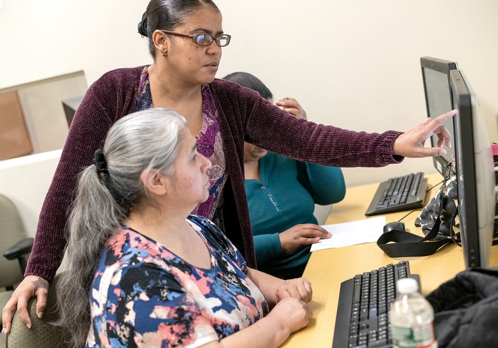 IN SESSION: Residents of Providence’s Olneyville neighborhood participate in on-site classes run by the library in cooperation with the Providence Housing Authority. Maria Quinonez, foreground, works with instructor Betty Tavares.  / PBN PHOTO/MICHAEL SALERNO