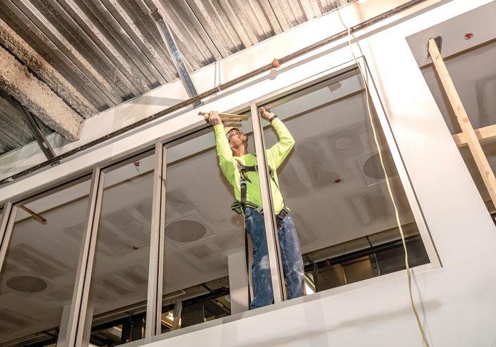 STOREFRONTS: Journeyman glazer Michael Bennacchia of Chandler Architects works on the interior storefronts during renovation of the Empire Street wing of the Providence Public Library.  / PBN PHOTO/MICHAEL SALERNO