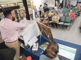 ONLINE PRESENCE: Auctioneer Travis Landry takes bids from the crowd, as well as online, during an auction at the Bruneau & Co. Auctioneers gallery in Cranston. Gallery owner and President Kevin Bruneau said most of their auctions feature online bidders from around the world competing with live audiences, pulling in up to 10,000 additional bidders who check in on auctions periodically. / PBN PHOTO/MICHAEL SALERNO