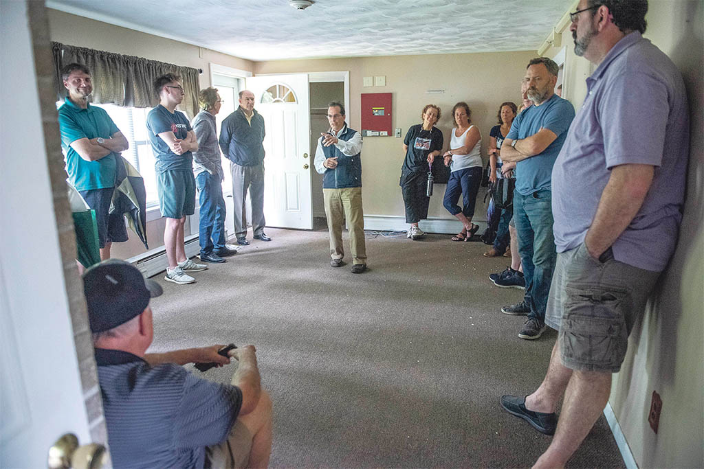 Center of attention: Auctioneer Sal Corio, center, president of SJ Corio Co. in Providence, collects bids in the living room of a 1,400-square-foot ranch at 365 Davisville Road in North Kingstown. The property sold for $205,000. / PBN PHOTO/DAVE HANSEN  