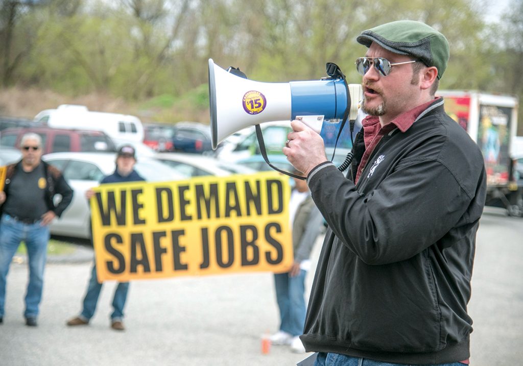BUSINESS MODEL: International Union of Painters and Allied Trades representative Justin Kelley leads a protest during a worker-safety rally outside the Hope Artiste Village in Pawtucket last year following a workplace accident that injured three workers. He said worker misclassification has become a business model for “a large portion” of the construction industry.   / PBN FILE PHOTO/MICHAEL SALERNO