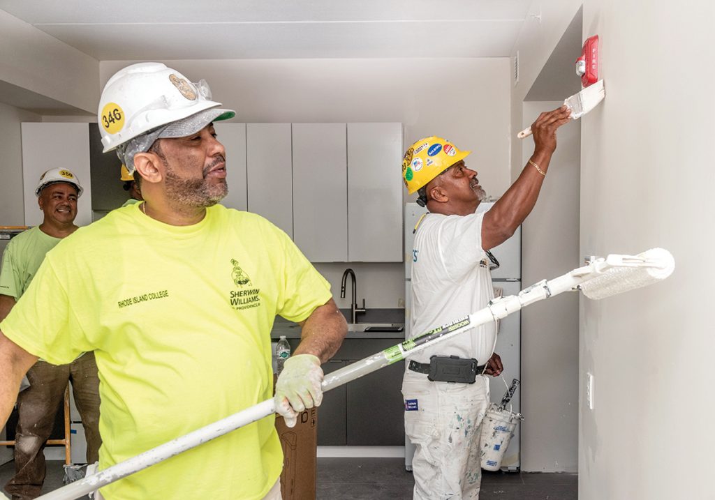 PUBLIC CONTRACTS: Jose Marcano, right, owner and president of Jomar Painting, works with members of his crew, Wilmer Escorcia, foreground, and Raphael Perdomo, to paint the 500-bed Brookside Apartments Complex at the University of Rhode Island. With state minority business enterprise certification, Marcano now focuses only on public contracts after losing out too often on private contracts to low bidders who don’t follow state labor laws.  / PBN PHOTO/MICHAEL SALERNO