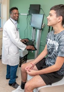 DOCTOR VISIT: Dr. Charlie Imonah speaks with patient Steven Vasquez of Cumberland at the new Blackstone Valley Neighborhood Health Station on Broad Street in Central Falls.  / PBN PHOTO/MICHAEL SALERNO