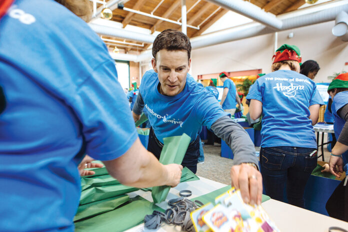 FUN, YES, BUT MUCH MORE: Hasbro CEO and Chairman Brian Goldner takes part in a 2016 companywide effort to pack toys for children and families, part of the company’s ongoing philanthropic efforts and one which its decision to cut back on plastic packaging is consistent with.   / PBN FILE PHOTO/ RUPERT WHITELEY