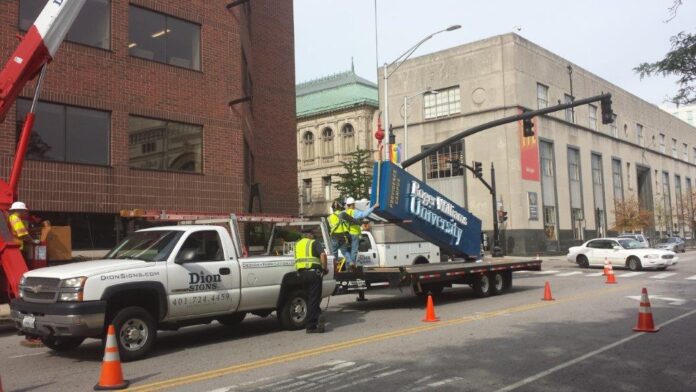 POYANT, BASED IN New Bedford, has acquired Dion Signs of Central Falls. Above, Dion Signs installing a sign for Roger Williams University. / COURTESY POYANT