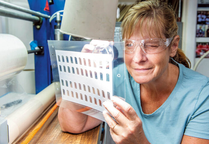 A CLOSE LOOK: NFI Corp. employee Kim Brittain inspects a laminate at the New Bedford company. PBN PHOTO/DAVE HANSEN