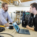 SETTING THE STAGE: Gareth Conner, left, founder and president of Creative Conners Inc., talks with automation technician Josh Stoller about a product Stoller is working on. It’s a Spotline Practical hoist used in theatrical shows.     PBN PHOTO/RUPERT WHITELEY