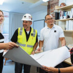 ACCORDING TO PLAN: From left, Assistant Project Manager Taylor Huntly, Superintendent Marty Mendonca, Senior Project Manager Chi Yik and Manager of Project Administration Sharon Barbary unfurl blueprints in the Providence office of Shawmut Design and Construction. PBN PHOTO/RUPERT WHITELEY