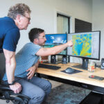 FLOOR PLANS: INSPIRE Environmental CEO Drew Carey, left, talks with Ben Taylor, a geographic information system specialist, at their Newport office. The company gathers imagery and data about the seafloor. Taylor creates visual representations of that information. PBN PHOTO/DAVE HANSEN
