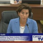 GOV. GINA M. RAIMONDO testified Tuesday in favor of a negotiated 20-year contract with IGT to continue to manage the state lottery.