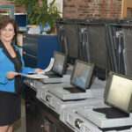 WHERE IT COUNTS: Secretary of State Nellie M. Gorbea, with the state’s ballot-counting machines. A task force is investigating whether the election system needs an upgrade to reduce its vulnerability to hackers.  / PBN PHOTO/MIKE SKORSKI