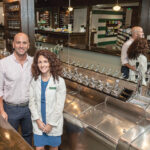 READY TO SERVE: Christina and Ken Procaccianti stand at the soda counter inside Green Line Apothecary in Providence, a throwback to independent pharmacies of an earlier era.   / PBN PHOTO/MICHAEL SALERNO